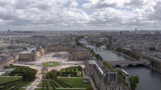 Aerial drone view flying sideways across the Louvre, Tuileries Garden, Seine River and Place du Carrousel surrounded by the historic Parisian skyline.
