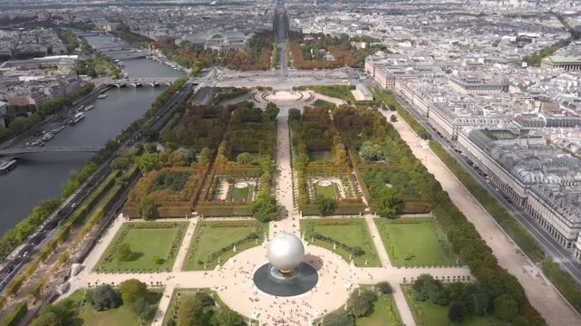A breathtaking aerial drone view over Paris captures the Tuileries Garden, the Seine River, the Olympic Games cauldron ball and the historic city skyline stretching into the horizon.