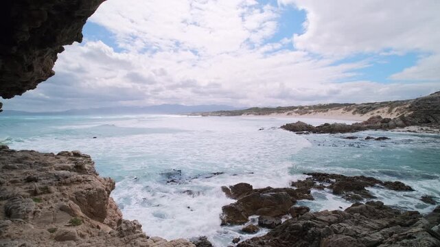 Waves roll into rocky bay and view toward Die Plaat in Walker Bay nature reserve