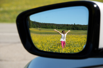 Girl in buttercup Field Reflected in car side mirror