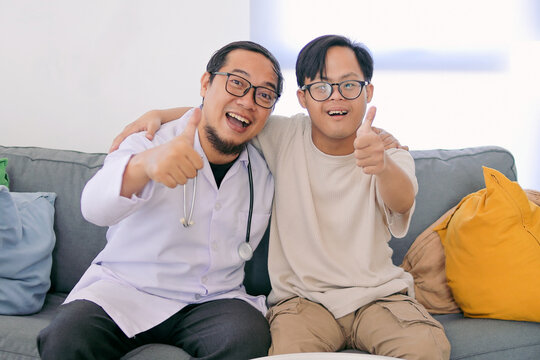 Asian Doctor and Patient Boy with Down Syndrome Share a Joyful Moment While Giving Thumbs Up