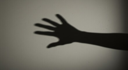 Fototapeta premium Dark hand casting sharp shadow on neutral wall, symbolic moody concept of fear or threat, generative ai