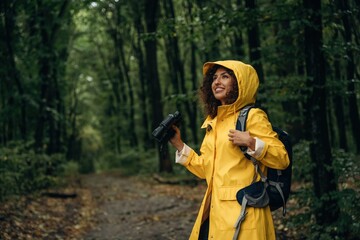 Obraz premium The binoculars, conception of discovery. Young woman enjoying nature in the forest under the rain