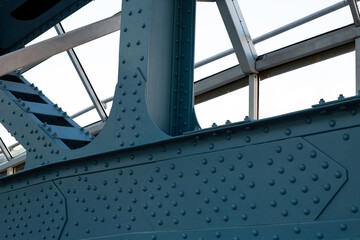 Close up of industrial steel bridge construction, blue painted structure with rivets and beams, modern architecture, geometric details and clear sky in the background