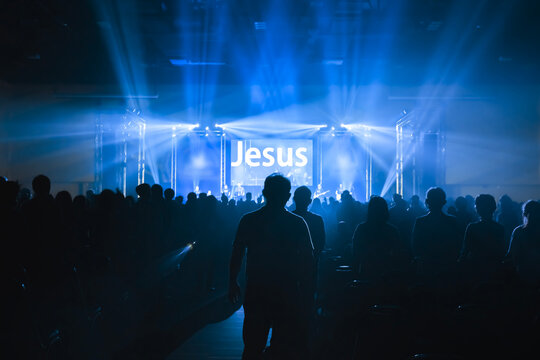 Worship includes music and numerous people lifting their hands in praise to God on stage 