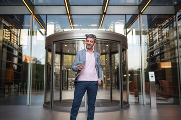 Obraz premium Casual businessman checking smartphone in modern office building