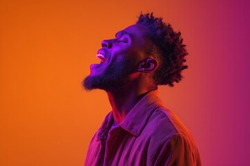 Joyful young african-american artist singing against a vibrant orange-purple studio backdrop illuminated by neon lighting, celebrating music, festivals, and hobbies.