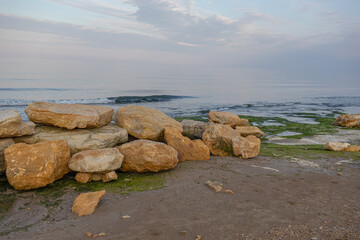 Large stones on the seashore. Evening landscape with a view of the stones by the sea. Sunset at the sea. Walking along the seashore.