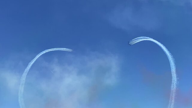 Air show Frecce Tricolori: Aerobatic display with contrails paints graceful loops in the vibrant, open blue sky, evoking freedom, skill, and the art of flight.