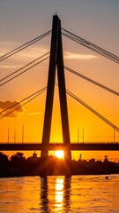 Obraz premium Silhouette of a cable-stayed bridge at sunset over a river