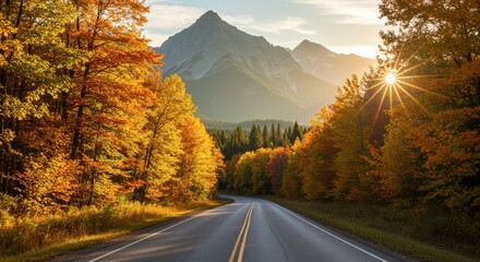 Scenic highway through autumn forest leading to mountain range illuminated by bright sunlight and clear sky
