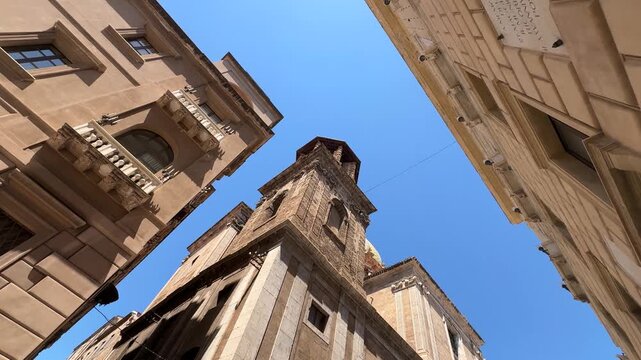 Rotating low angle tracking shot looking up at the historic side tower of the San Giuseppe dei Teatini church along Via Maqueda in Palermo, Sicily, Italy.