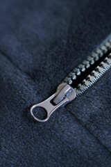 Metal zipper on blue fleece fabric. Macro photography of clothing.