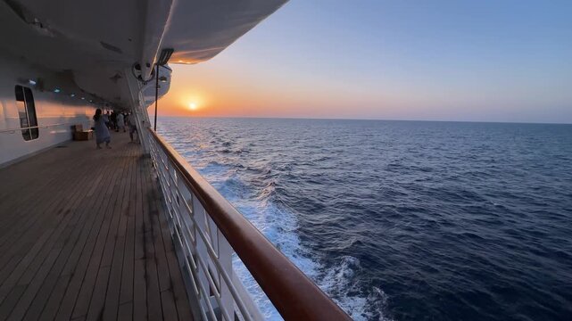 Wide angle boat POV from the lower wooden deck of a luxury cruise ship showing the ocean wake while sailing into the sunset near Mallorca, Spain.