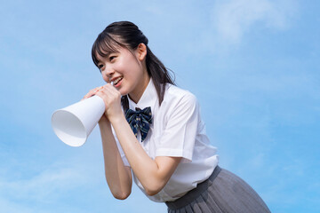青空をバックに応援する高校生