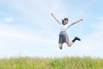 青空をバックにジャンプする高校生