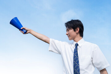 青空をバックに応援する高校生