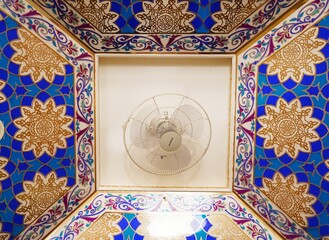 Fan with blue colorful patterned ceiling background. Beautiful fan vaulted ceiling. 
