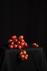 View of a bunch of red grapes on a table and a black background, vertically with copy space