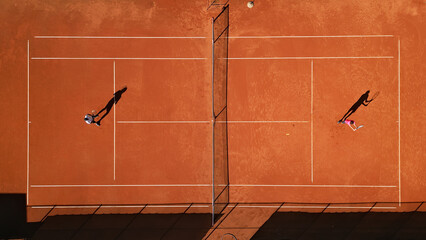 Drone shot of two athletes practicing on a clay tennis court, highlighting dynamic movement and focus. Captures intense training, skill development, and competitive spirit.