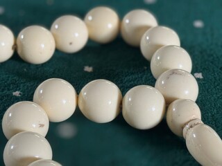A close-up of a white prayer bead (tasbih) resting on an emerald green carpet, symbolizing faith, devotion, and the serenity of Islamic spirituality.