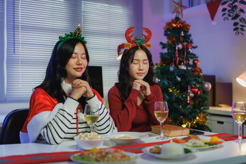Two young women praying at christmas dinner