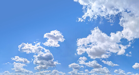 Panorama blue sky with white fluffy clouds. Copy space on panorama of cumulus clouds drifting calmly across the sky toward the viewer. A majestic spectacle of nature's elements.