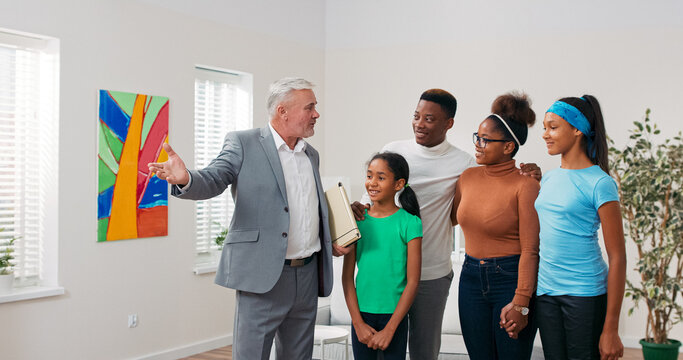 A real estate agent walks through the apartment with a smiling family, explaining features of each room. The parents listen, while the daughters explore with curiosity. - Powered by Adobe