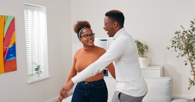 A cheerful couple of lovers enters the living space of their new home, looks around with satisfaction, hugs out of happiness, excited to begin a new chapter.