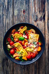 Italian ravioli soup with vegetables on wooden table