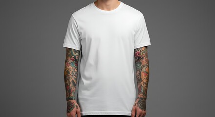 A man with tattoos on his arms wearing a white t-shirt stands against a gray background.