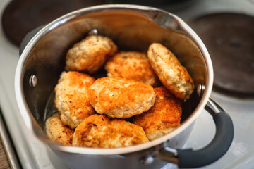 Multiple fried chicken patties stacked in a metal pot for keeping warm and steaming