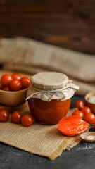 Tomato sauce jar with fresh tomatoes on a rustic background.