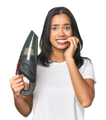 Latina with vacuum, cleaning concept biting fingernails, nervous and very anxious.
