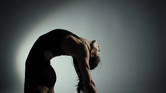 Flexible Woman in Black Leotard Bending Backwards Under Spotlight Toned Figure in Dance Position Against a Gradient Background Creates a Dynamic Silhouette for Bodily Expression