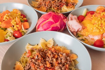 Fitness nutrition bowls with pasta, lean meat and fresh vegetable salad. Balanced diet with corn, peppers, lettuce and tomatoes. Healthy lifestyle and clean eating background for diet concept.