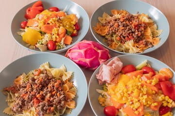 Fitness nutrition bowls with pasta, lean meat and fresh vegetable salad. Balanced diet with corn, peppers, lettuce and tomatoes. Healthy lifestyle and clean eating background for diet concept.