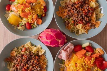 Fitness nutrition bowls with pasta, lean meat and fresh vegetable salad. Balanced diet with corn, peppers, lettuce and tomatoes. Healthy lifestyle and clean eating background for diet concept.