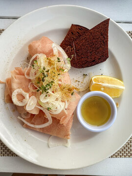 Thin slices of raw bonito fish served in the stroganina style with onion, sprouts, and a lemon wedge