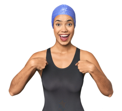Pro Latina swimmer in studio gear surprised pointing with finger, smiling broadly.