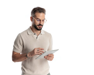 casual young man with glasses looking and touching tablet screen