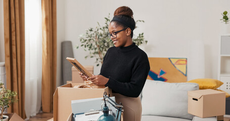 A mother sorts through boxes after moving into her new house. She holds a picture frame close and smiles gently, remembering her childhood and the people she loves.