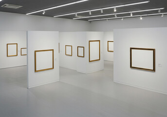 Empty gallery spaces with modern white walls and gold framed blank canvases invite creative display