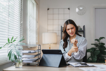 Asian businesswoman suffering wrist pain while working from home office