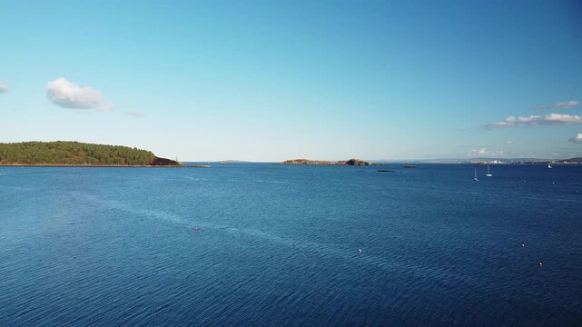 Inchcolm Island and its medieval Abbey, viewed across the Firth of Forth from Dalgety Bay, Fife, Scotland. A serene vista of Scottish history and the coastline.

