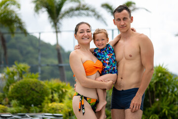 Happy family posing together by hotel poolside