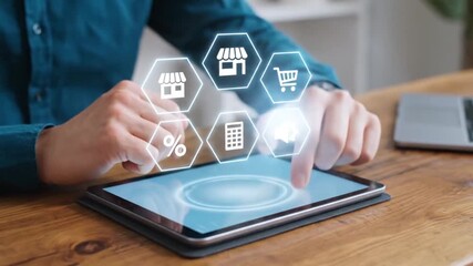 Person using a tablet with holographic icons representing online shopping sales marketing and business management concepts - Powered by Adobe