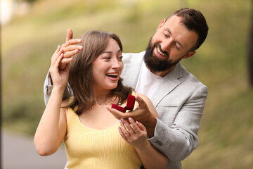 Man with engagement ring making marriage proposal to his girlfriend outdoors