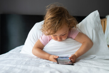 Baby girl playing with smartphone on bed