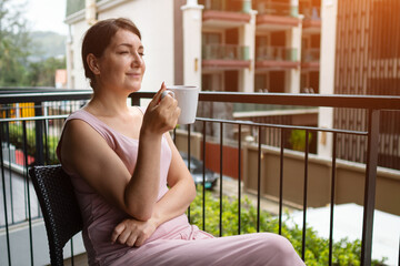 Woman relaxing on balcony drinking coffee and enjoying view